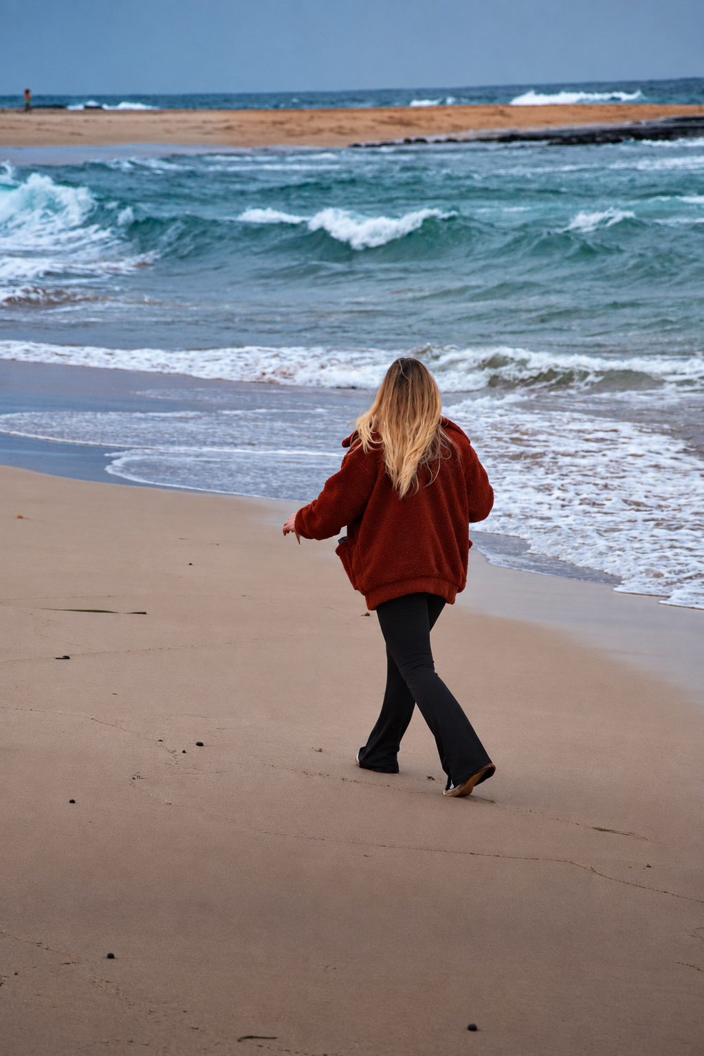 Person walking along the beach beside the ocean